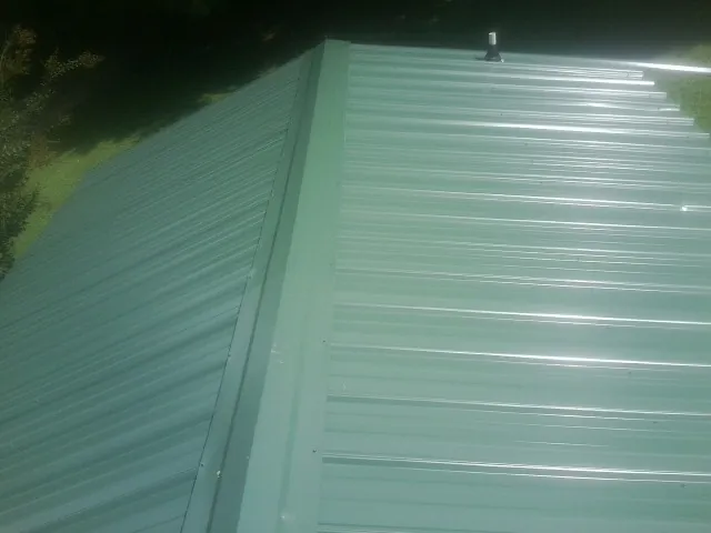 New green metal panels meeting at the ridge of a roof — Flat Roof Repair work by our crew in Centerville