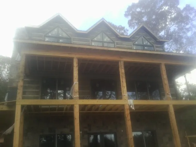 Dormers and porch framing on a large log home under construction — Roof Coating work by our crew in Centerville