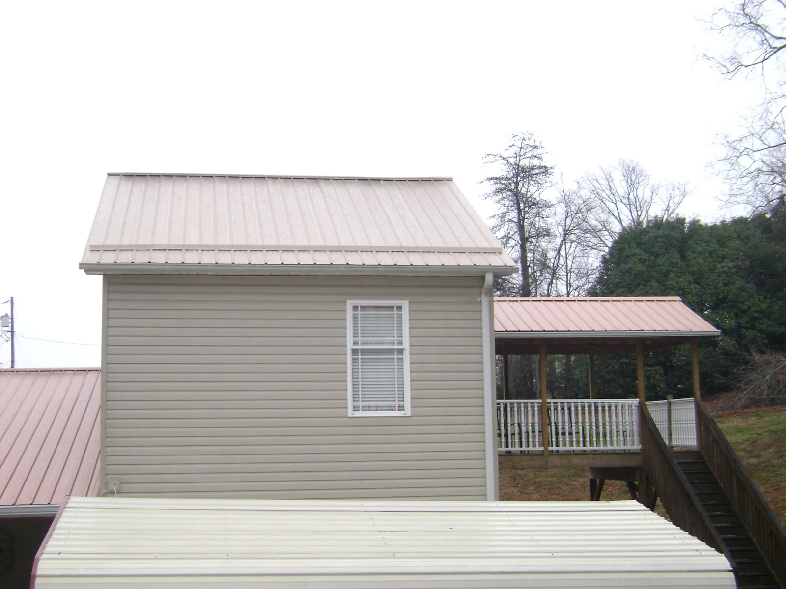 Tan metal roofs on a two story addition and attached porch, from a Roof Replacement job in Centerville